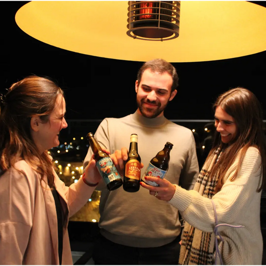 Três amigos a brindarem com cervejas artesanais durante a noite