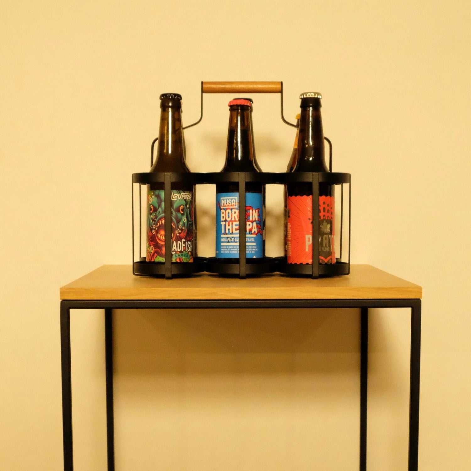 Cervejas artesanais em pack estilizado para fácil transporte em fundo branco e apoiadas em mesa