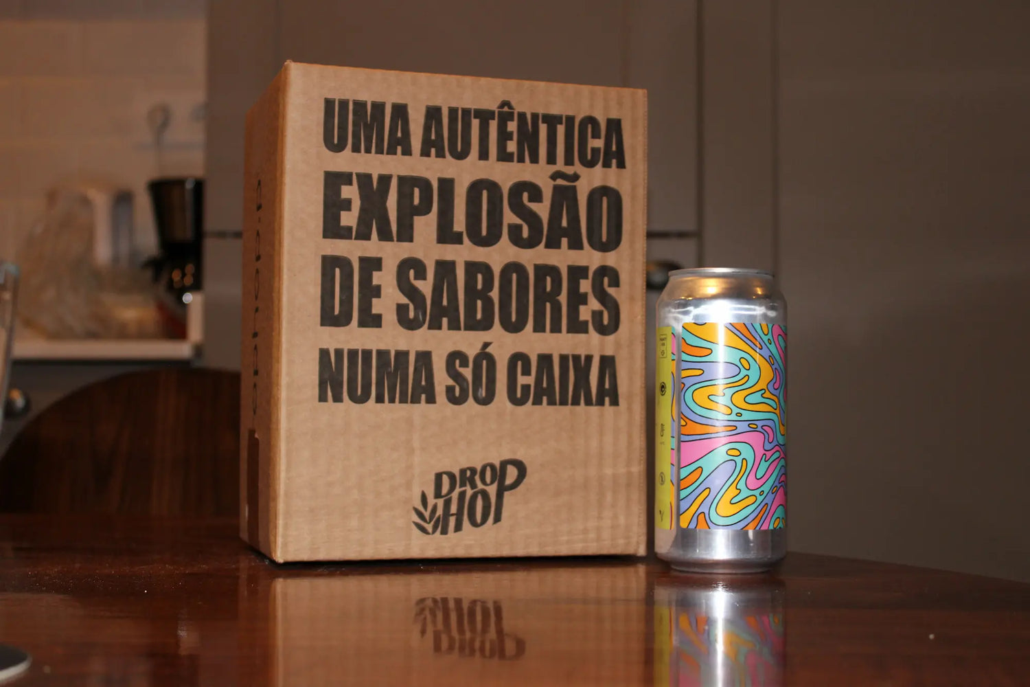 Pack da Drop Hop de cerveja artesanal com mensagem escrita na caixa, pousado numa mesa junto com uma lata de cerveja