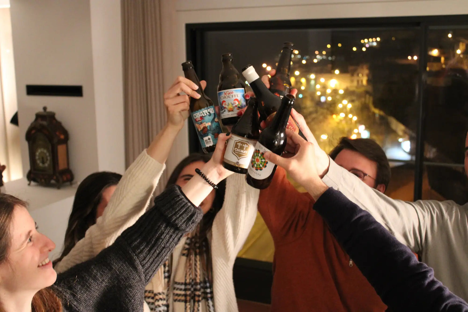 Seis pessoas a brindarem dentro de casa com cervejas artesanais em ambiente de festa